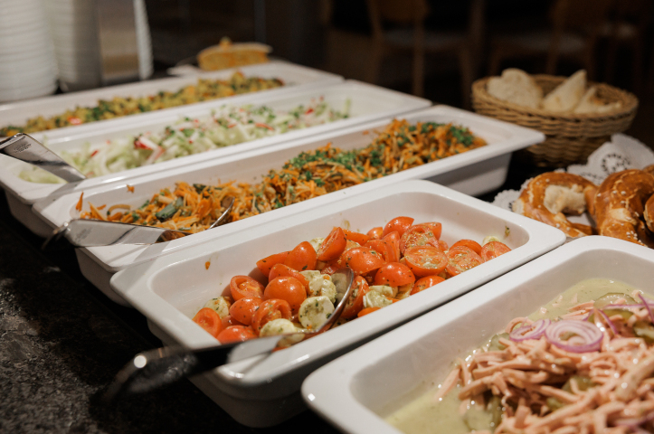 Buffet mit verschiedenen Salaten, Tomaten und Beilagen.