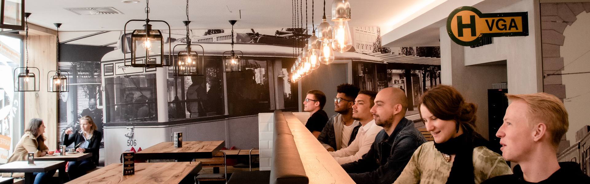 Gemütliche Bistro-Szene mit Gästen an Tresen und Tischen.