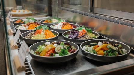 Mehrere frisch angerichtete Salatschüsseln in einer Auslage.