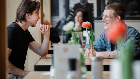 Zwei Männer sitzen in einem Restaurant und unterhalten sich an einem Tisch.
