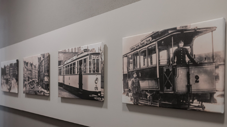 Schwarz-weiße Fotografien historischer Straßenbahnen an einer Wand.