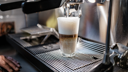 Frisch zubereiteter Latte Macchiato in einer Kaffeemaschine.